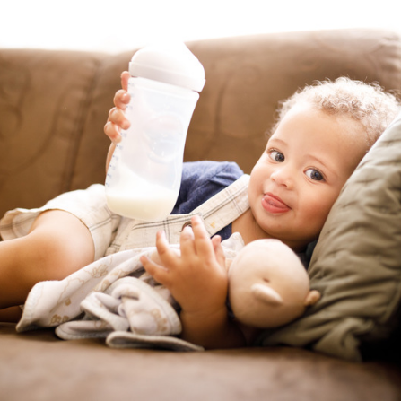 un enfant tient son doudou et son biberon