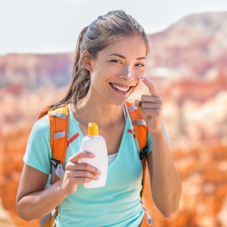 Une femme en randonnée sur met de la crème solaire sur le visage