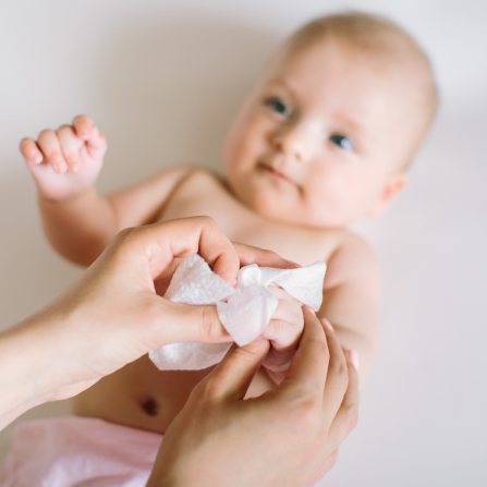 Une maman nettoie les mains de son bébé à l'aide d'une lingette