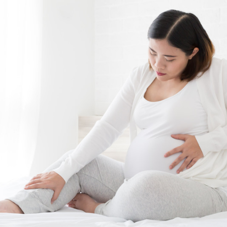 Une femme enceinte, assise, souffre d'une sensation de jambes lourdes