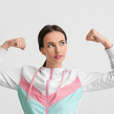 Une femme avec une veste de sport serre ses poings pour montrer sa force
