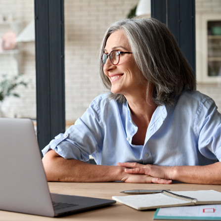 Une souriante porte des lunettes pour travailler sur son ordinateur