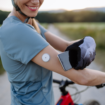 Une femme surveille sa glycémie via un capteur de glucose lors d'une sortie à vélo