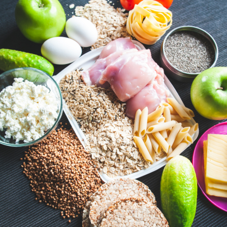 Une table comporte plusieurs aliments parfaits à consommer chez le sportif : blancs de poulet, pommes, oeufs, fromage, céréales, etc