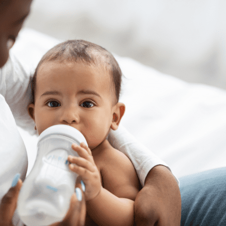 Bébé boit au biberon dans les bras de sa mère