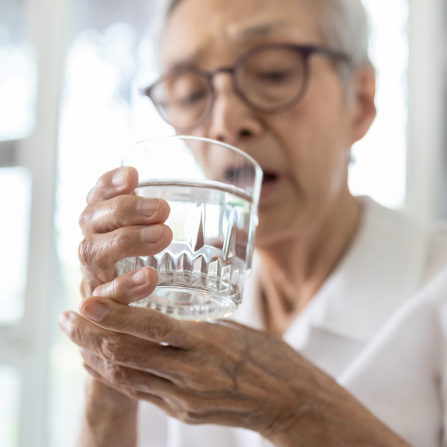 Personne âgée en maison de retraite buvant un verre d'eau pour maintenir une bonne santé