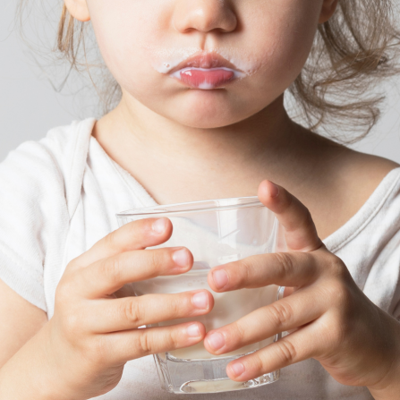 Une enfant boit du lait de vache dans un verre