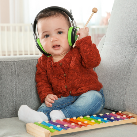Une enfant qui joue du xylophone a un casque anti-bruit sur les oreilles