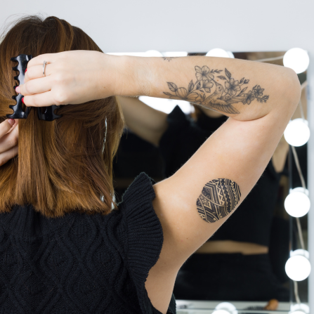 Une femme en train de se coiffer protège son capteur de glycémie avec le patch tatoo Capteur Protect