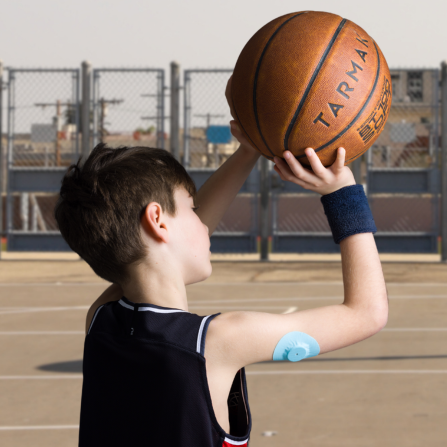 Un enfant jour librement au basket grâce au patch bleu clair Capteur Protect qui protège son capteur de glycémie