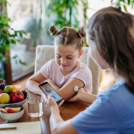 Une mère assure le suivi du taux de glucose de sa fille via son capteur de glycémie