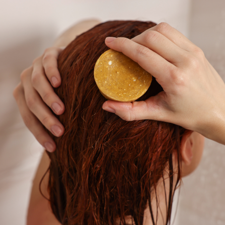 Une femme se lave les cheveux en frottant le shampoing solide