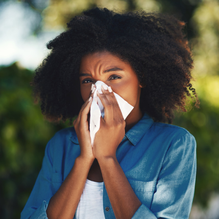 Une femme se mouche en raison d'une allergie au pollen