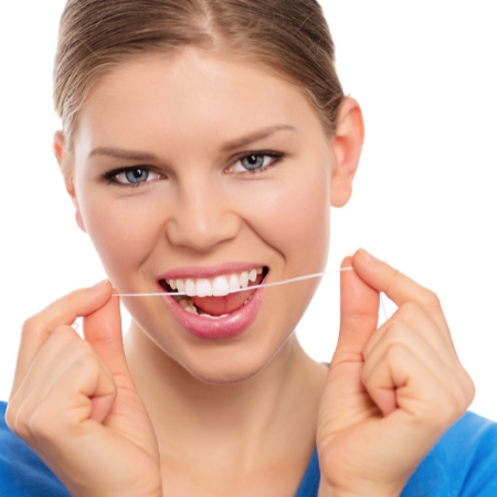 Femme souriante utilisant un fil dentaire