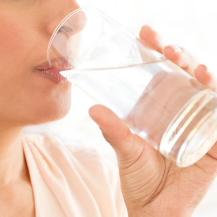 Une femme boit un grand verre d'eau
