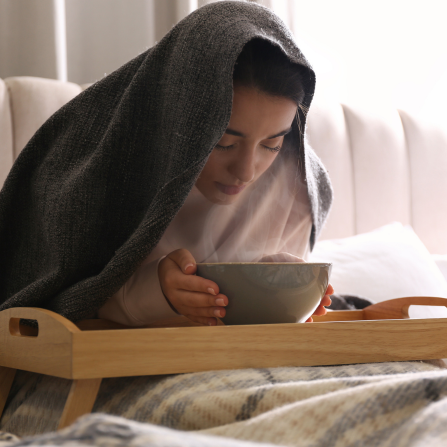 Une femme est dans son lit et fait une inhalation pour soigner un rhume