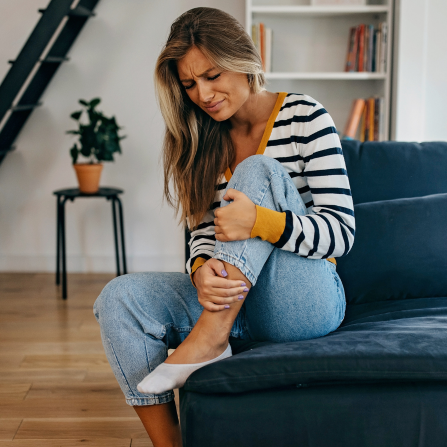 Une femme maintient sa jambe pour soulager une crampe
