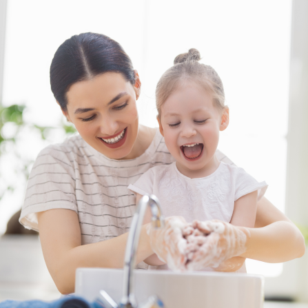 Une mère et sa fille se lavent les mains en souriant