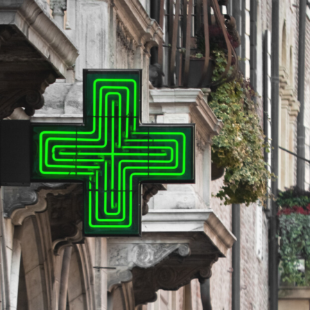 La croix verte de la pharmacie est visible sur le côté d'un bâtiment