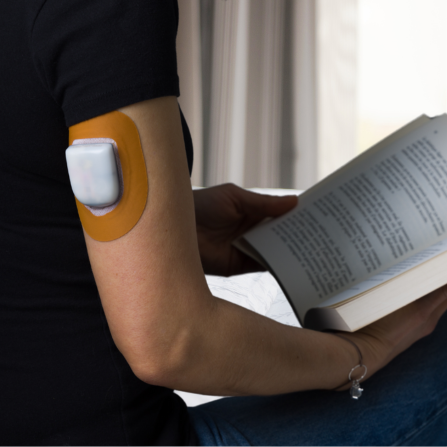 Une femme en train de lire porte une pompe patch protégée par un patch Capteur Protect