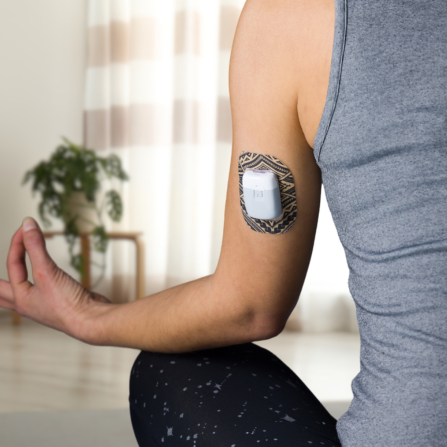 Une femme protège sa pompe à insuline avec un patch Capteur Protect pour pouvoir faire du yoga librement, sans penser au risque de décollement