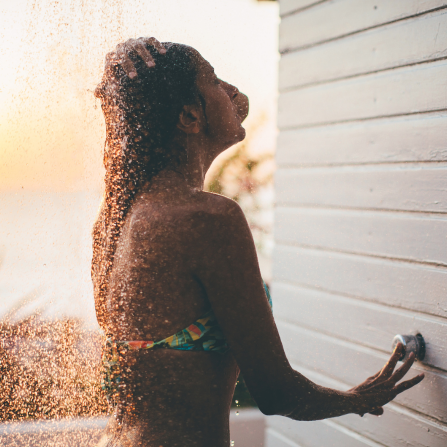 Une femme se rince les cheveux après une journée à la plage