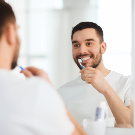 Une homme se brosse les dents face à un mirroir