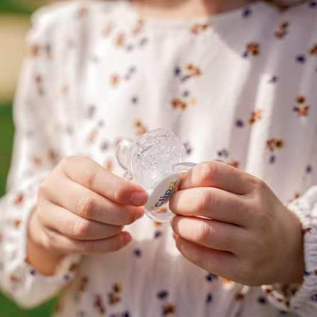 Une petite fille tient la tétine clipp avec plusieurs collerettes clipsées entre ses mains