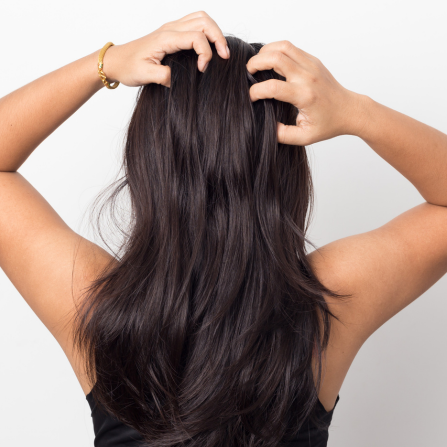 Une femme de dos passe les mains dans ses cheveux