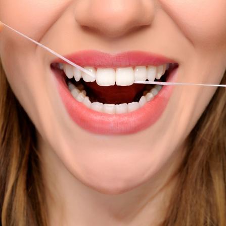 femme utilisant un fil dentaire