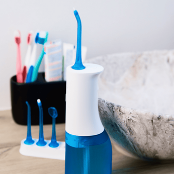 Hydropulseur posé sur une table à coté des brosses à dents