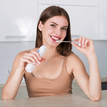 femme utilisant une brosse à dents et un hydropulseur